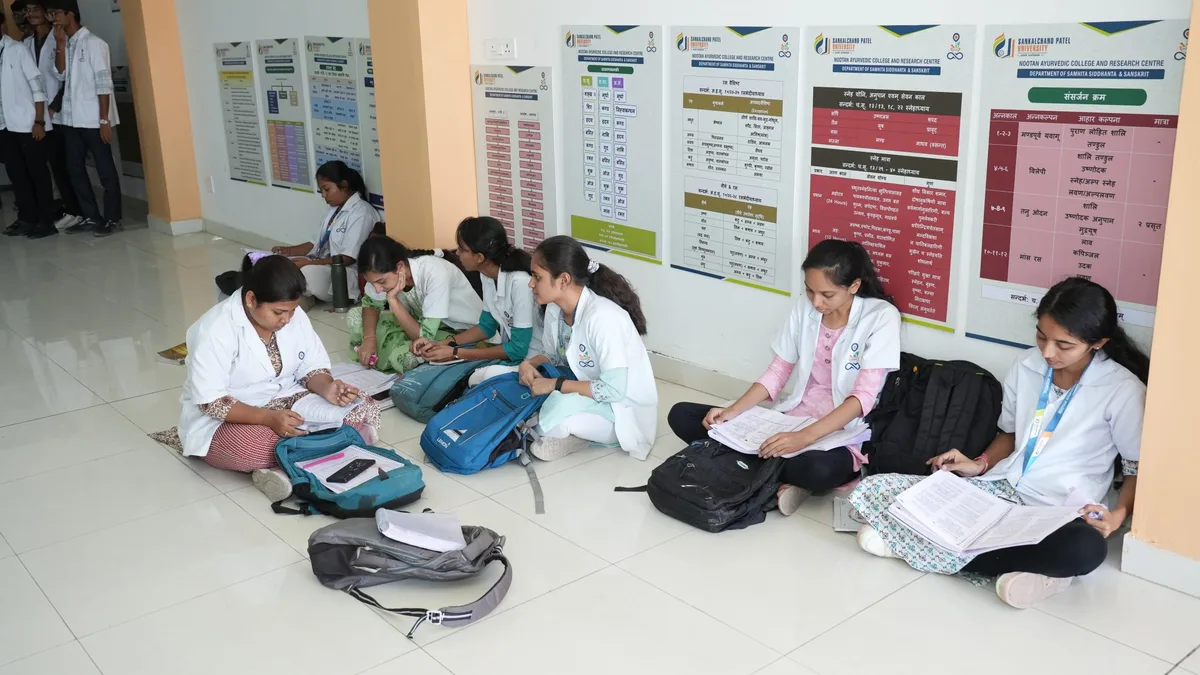 Ayurveda college students in white coats studying outside a department classroom in India
