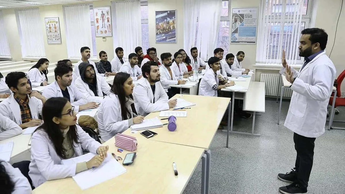 Medical students in white coats sitting in a classroom during a lecture
