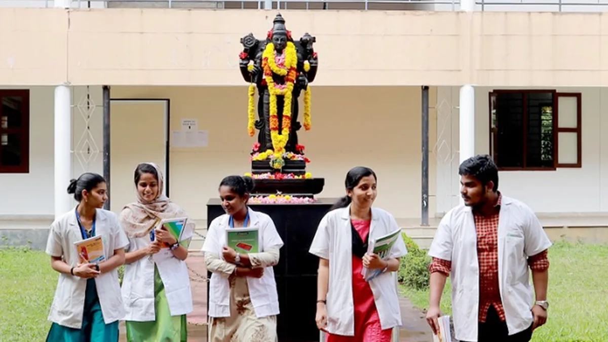 Students in white coats walking through the campus of an Ayurveda medical college in Kerala