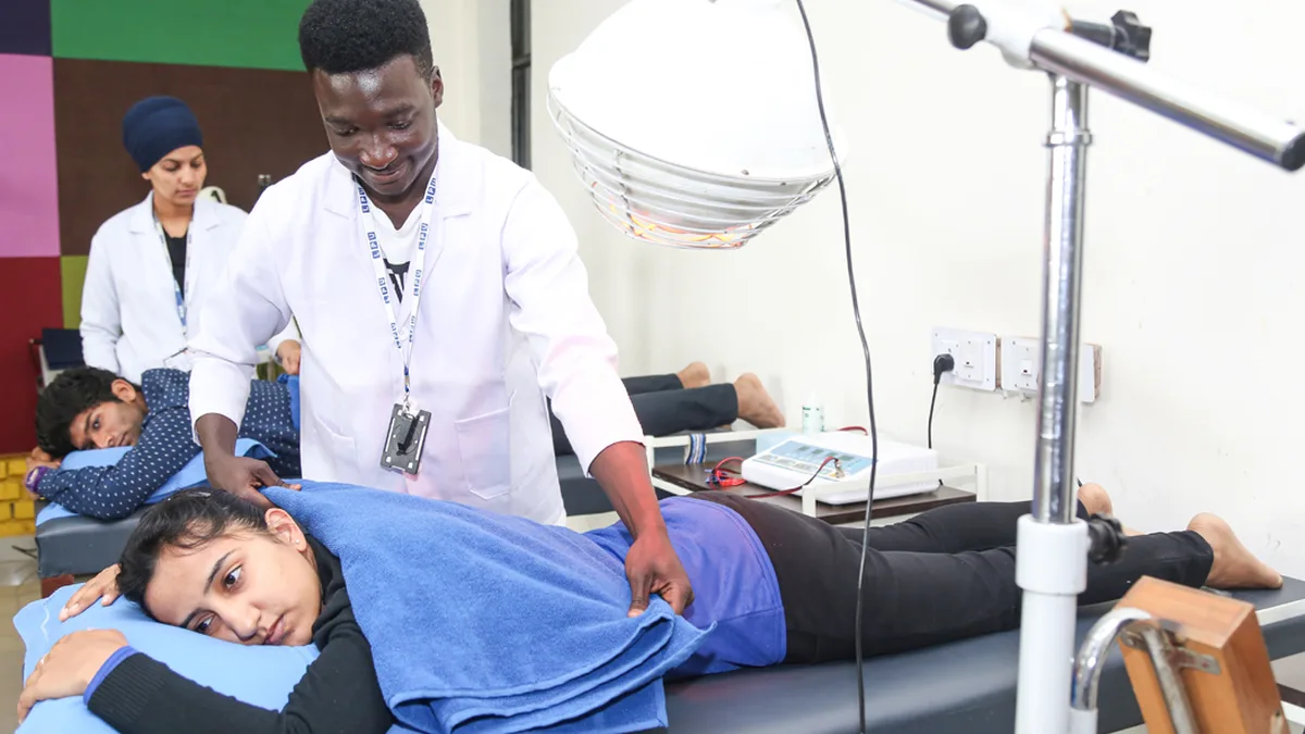 Physiotherapy students practising therapy techniques in a college training lab
