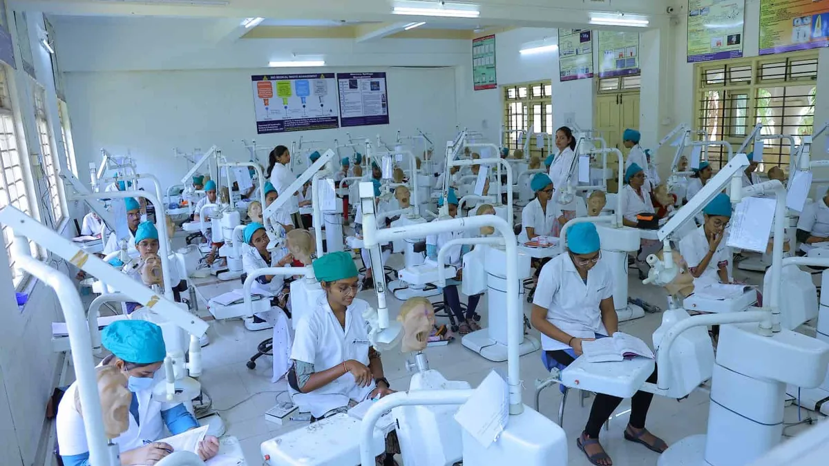Dental students in white coats practising in a dental college lab in India