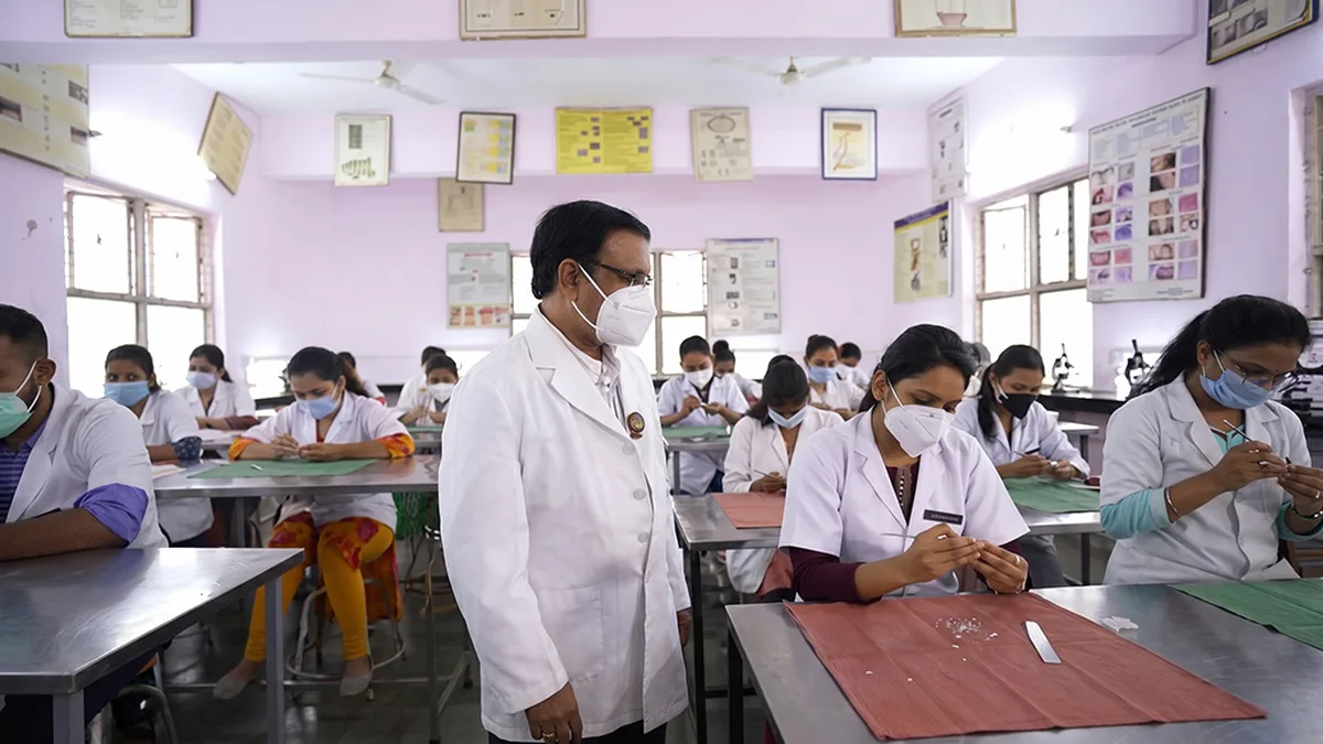 Dental students in white coats practising in a dental college lab in India