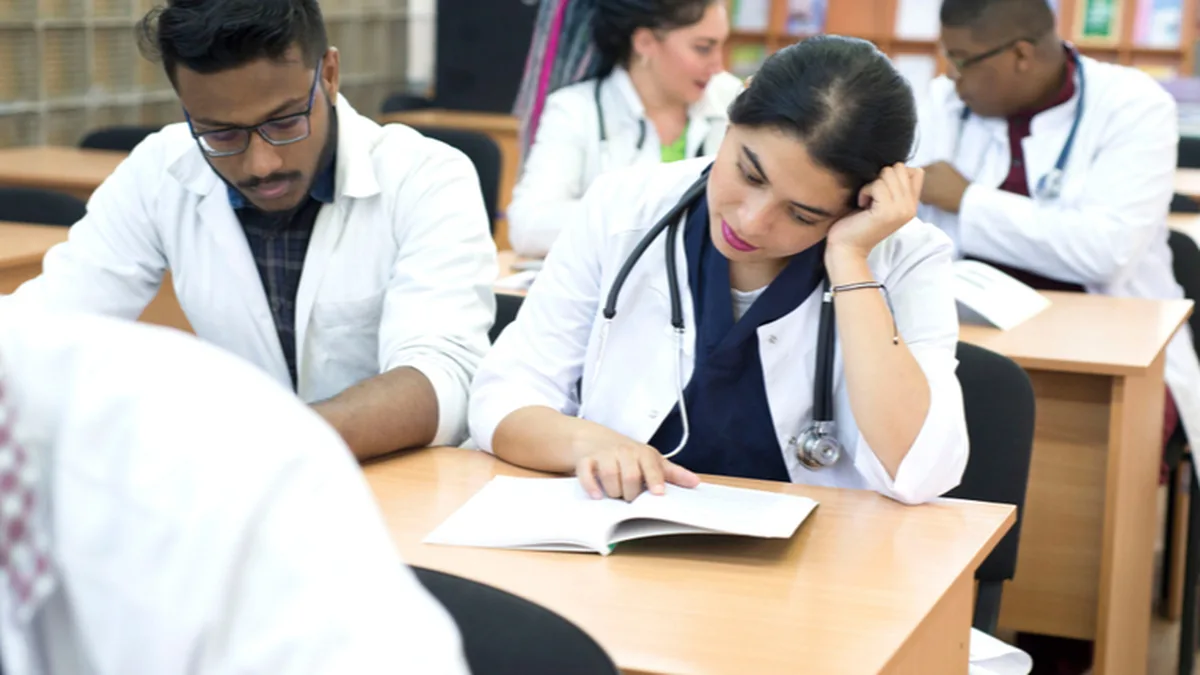 Medical students in white coats walking through a hospital corridor during admission season