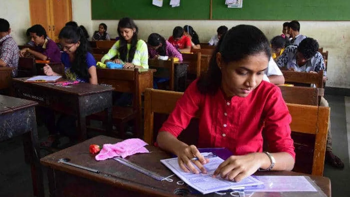 Students writing a written entrance examination inside an Indian classroom