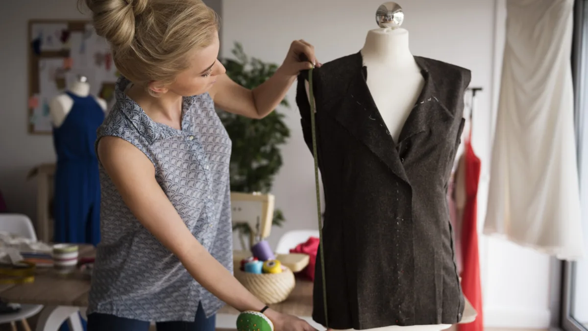 A fashion design student pinning fabric on a dress form in a design workshop