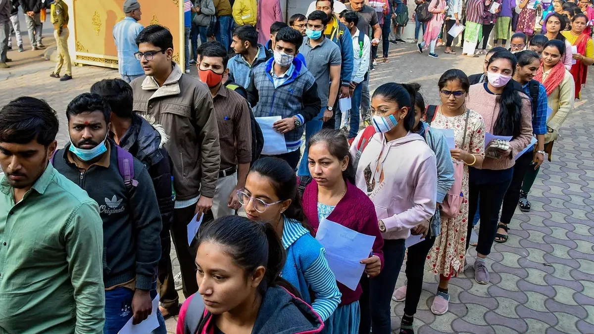 Candidates queueing outside an exam centre with their admit cards in hand